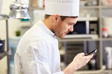 chef che utilizza lo smartphone nella cucina di un ristorante
