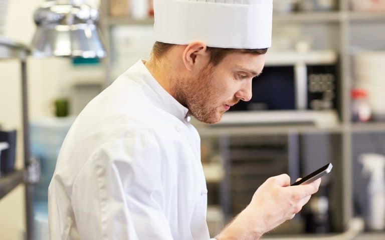 chef che utilizza lo smartphone nella cucina di un ristorante